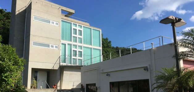 沖縄売買不動産 中古一戸建て「うるま市与那城平安座」の写真1。コンクリート打ち放しのお洒落な外観。赤瓦の別棟と良い対比になっています。